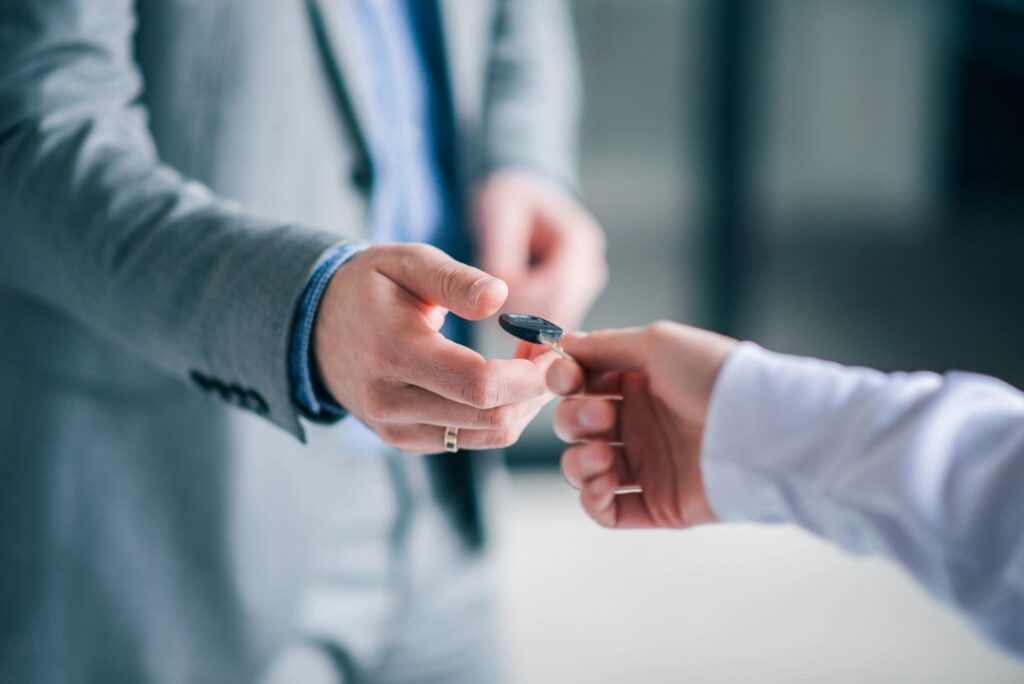 Close-up image of businessman handing over the keys to a client.